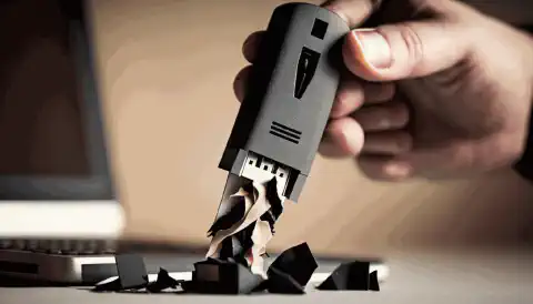Das Bild einer Person, die einen USB-Stick in der Hand hält, mit einem Schredder im Hintergrund